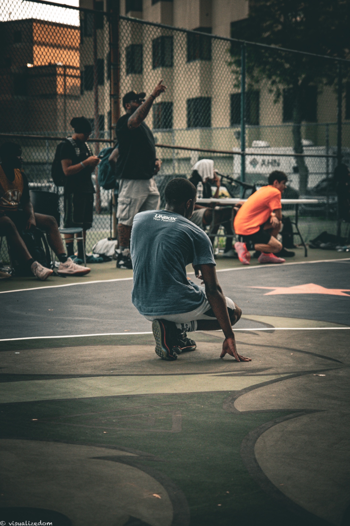 Youth basketball player crouched with the ball on an outdoor asphalt court